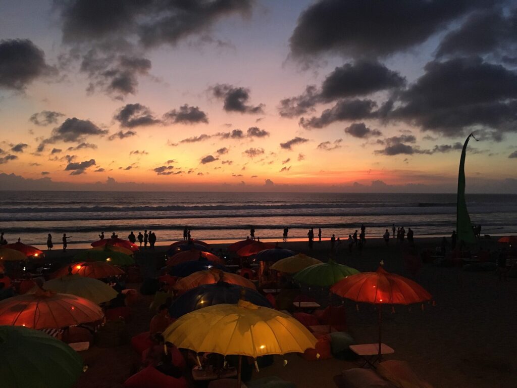Pantai Seminyak saat matahari turun dengan deretan payung di pasir