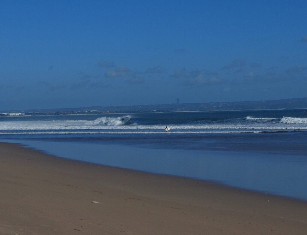 Hamparan pasir Pantai Seminyak dengan ombak di tepi barat